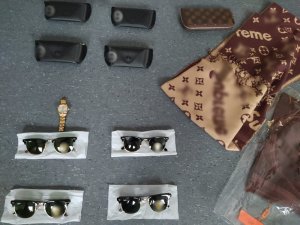 Na zdjęciu widoczne są przedmioty takie jak okulary, zegarek i odzież, zabezpieczone przez policjantów a pochodzące z przestępstwa