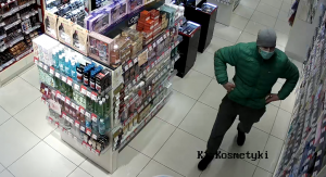 Na zdjęciu widoczny jest mężczyzna chowający kosmetyki do kieszeni kurtki