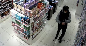 Na zdjęciu widoczny jest mężczyzna chowający kosmetyki do kieszeni kurtki