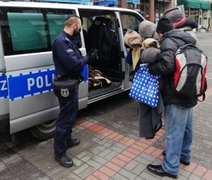 Na zdjęciu widoczni są policjanci rozdający odzież osobom bezdomnym