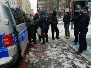 Na zdjęciu widoczni są policjanci, którzy rozdają z radiowozu odzież osobom potrzebującym