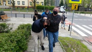 Na zdjęciu widoczni są zatrzymani prowadzeni przez nieumundurowanych policjantów