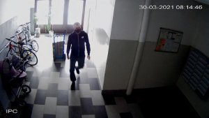 Na zdjęciu widoczny jest mężczyzna wchodzący do klatki schodowej