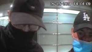 Na zdjęciu widoczni są dwaj mężczyźni stojący przed bankomatem