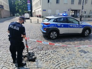 Na zdjęciu widoczny jest policjant zabezpieczający  uszkodzoną nawierzchnię