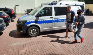Na zdjęciu widoczny jest zatrzymany mężczyzna prowadzony przez policjanta