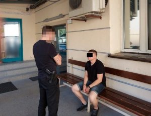 Na zdjęciu widoczny jest zatrzymany mężczyzna siedzący na ławce