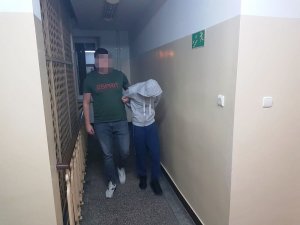 Na zdjęciu widoczny jest zatrzymany mężczyzna prowadzony przez policjanta