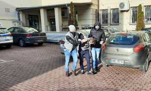 Na zdjęciu widoczny jest zatrzymany mężczyzna prowadzony przez policjantów