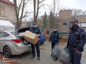 Na zdjęciu widoczni są policjanci z zebranymi dla bezdomnych ubraniami