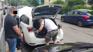 Na zdjęciu widoczni są policjanci podczas czynności z zatrzymanym mężczyzną.