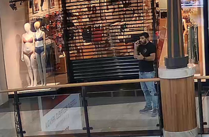 Na zdjęciu widoczny jest mężczyzna chodzący po galerii handlowej