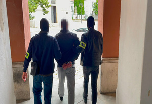 Policjanci prowadzą zatrzymanego do sprawy zniszczenia mienia w galerii rękodzieł