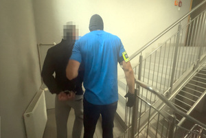Policjanci prowadzą zatrzymanego do sprawy zniszczenia mienia w galerii rękodzieł